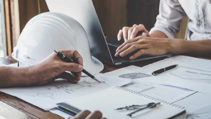 Zwei Ingenieure arbeiten zusammen an technischen Zeichnungen und Bauplänen