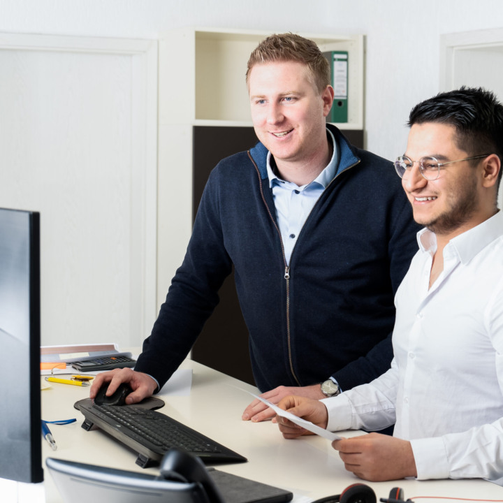Mitarbeiter Stefan und Paiman besprechen sich vor Computer