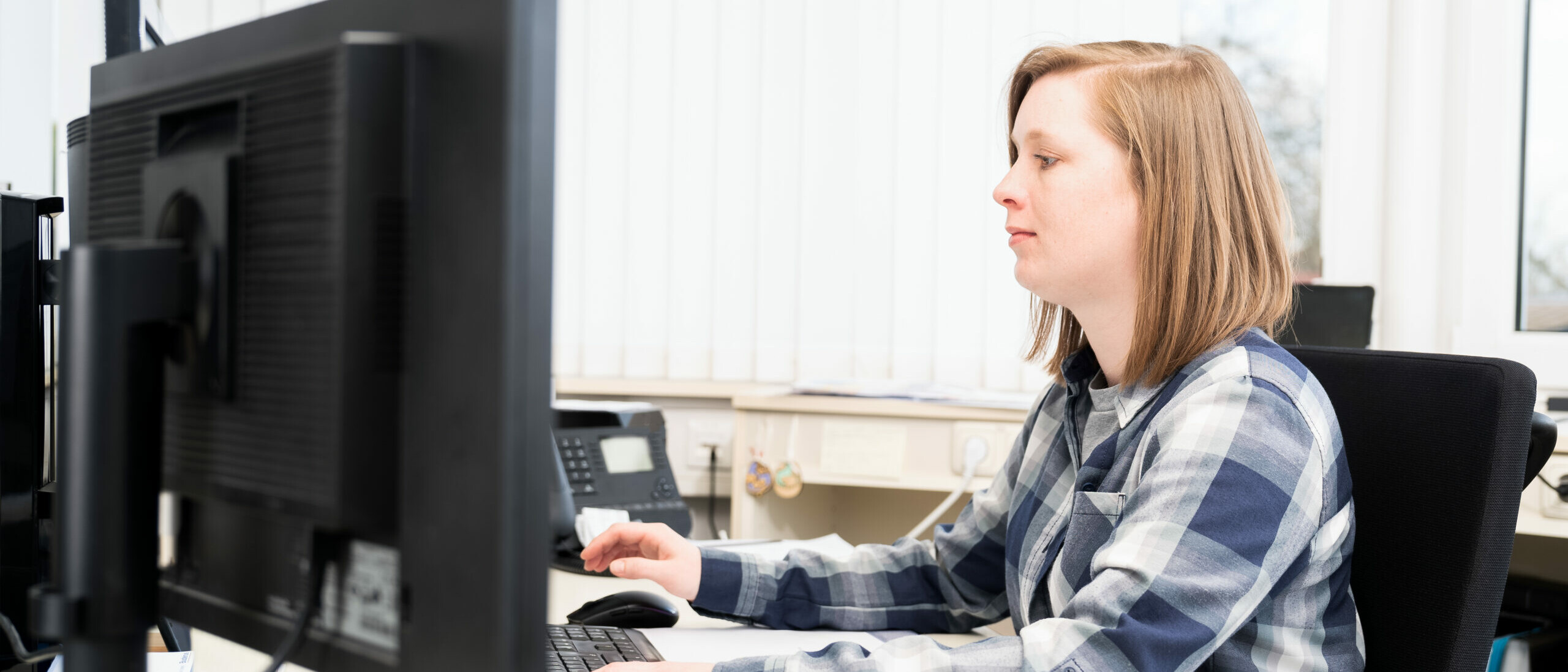 Mitarbeiterin Kathrin arbeitet an ihrem Arbeitsplatz am Computer