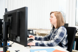 Mitarbeiterin Kathrin arbeitet an ihrem Arbeitsplatz am Computer